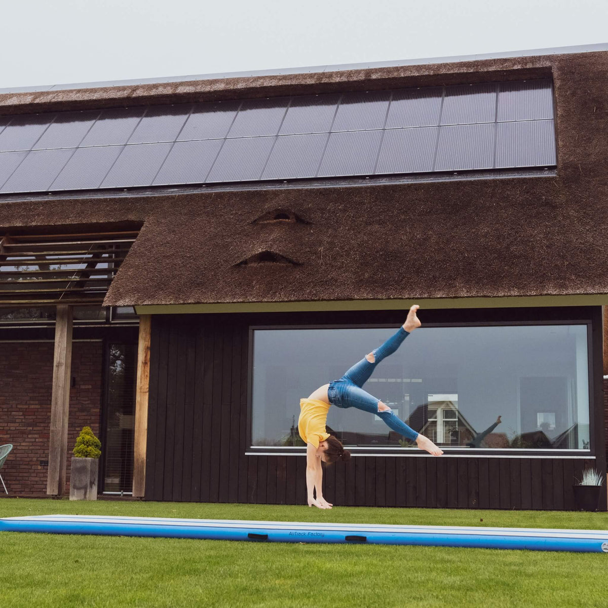 Gymnastin turnt draußen auf einem blauen AirTrack Factory AirFloor, steigert Technik und Ausdauer, verfügbar bei PureGymnastics.de